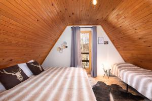 two beds in a room with a wooden ceiling at Cottage Gordana in Begovo Razdolje