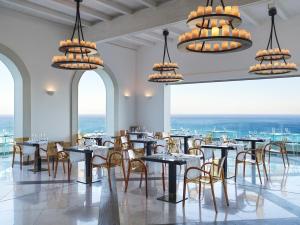a dining room with tables and chairs and chandeliers at Esperos Village Blue & Spa - Adults Only in Faliraki