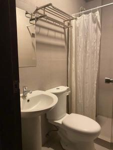a white bathroom with a toilet and a sink at Travelers Inn Matina in Davao City