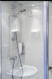 La salle de bains est pourvue d'une douche et d'un lavabo. dans l'établissement Grand Hôtel d'Espagne, à Lourdes