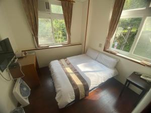 1 dormitorio pequeño con 1 cama y 2 ventanas en Lu-Lin B&B, en Wufeng