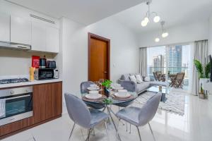 Delightful 2BR apartment at Reva Residences في دبي: مطبخ وغرفة معيشة مع طاولة وكراسي