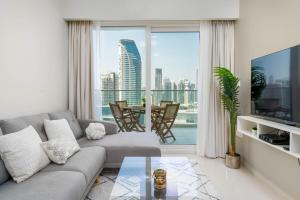 een woonkamer met een bank en een groot raam bij Delightful 2BR apartment at Reva Residences in Dubai