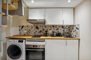 a kitchen with white cabinets and a washer and dryer at Hyper centre Écusson - Magnifique T1 au calme in Montpellier +1 photo