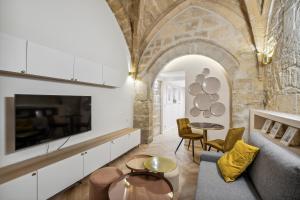 ein Wohnzimmer mit einem Sofa und einem TV in der Unterkunft Hyper centre Écusson - Magnifique T1 au calme in Montpellier