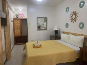 - une chambre avec un grand lit et une couverture jaune dans l'établissement Pensio de Felipe, à Tagaytay