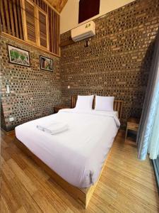 a large white bed in a room with a brick wall at Đường Lâm Village in Sơn Tây
