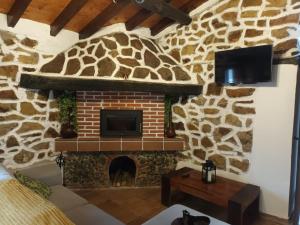 sala de estar con chimenea de piedra y TV en La cabaña de Seña, en Laredo