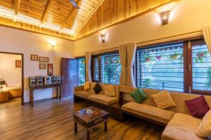 a living room with a couch and a table at SaffronStays Gardens On The Lake, Bhimtal - pet-friendly garden villa by the lake in Bhīm Tāl