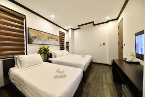 a hotel room with two beds and a flat screen tv at Kingdom Hotel Hanoi in Hanoi