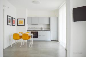 una cucina bianca con tavolo e sedie gialle di Homiday - Residenza Caravelle a Pineto