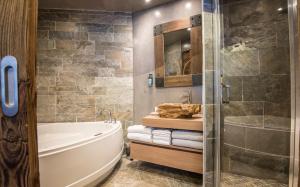 a bathroom with a tub and a glass shower at Les Grands Montets Hotel & Spa in Chamonix-Mont-Blanc