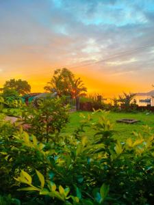 una puesta de sol sobre un campo con árboles y hierba en RiverStone RiverFront FarmHouse, en Gokarna