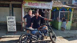 西里古里的住宿－Atathi Niwas Guest House for Backpackers and Travellers，两个人站在摩托车旁边