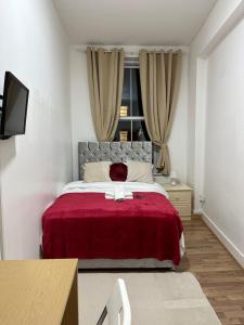 a bedroom with a bed with a red blanket and a window at City Lodge Shadwell in London