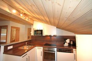 cocina con armarios blancos y techo de madera en Ferienwohnung Königsleiten 2 - Top 1, en Wald im Pinzgau