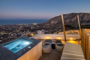 a hot tub on a balcony with a view of a city at Santorini Soul Villas in Pirgos