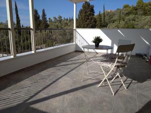 patio con mesa y sillas en el balcón en VILLA NDJ RELAX, en Tsoukaladhes
