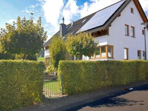 een wit huis met een zonnedak en een heg bij Ferienwohnung Quinkert in Eslohe