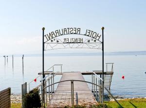 un quai en bois avec un panneau sur l'eau dans l'établissement Hotel Heinzler am See, à Immenstaad am Bodensee