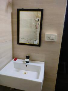 y baño con lavabo blanco y espejo. en RiverStone RiverFront FarmHouse, en Gokarna
