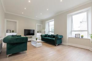 a living room with two green couches and a flat screen tv at Luxury 3 Bed Apartment in Aberdeen City Centre. in Aberdeen