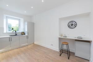 eine Küche mit einer Uhr an der Wand und einem Stuhl in der Unterkunft Luxury 3 Bed Apartment in Aberdeen City Centre. in Aberdeen