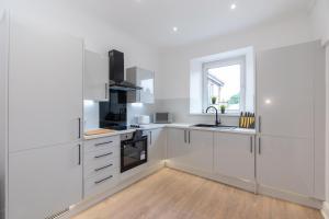cocina blanca con armarios blancos y ventana en Luxury 3 Bed Apartment in Aberdeen City Centre. en Aberdeen