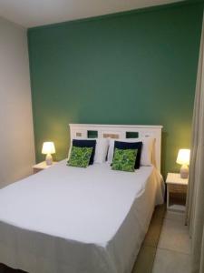 a bedroom with a white bed with a green wall at Riverwalk Villa 