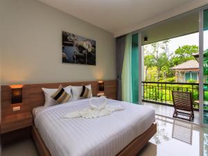 a bedroom with a large bed and a balcony at Khaolak Forest Resort in Khao Lak