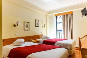 a hotel room with two beds and a window at Residencial Colombo in Funchal