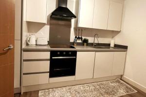 a small kitchen with a stove and a sink at Cosy 1 bedroom apartment with car park space. in West Bromwich