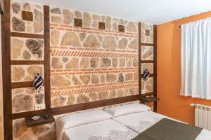Un dormitorio con una pared de piedra y una cama en La Casona de Trescasas, en Sonsoto