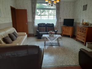 ein Wohnzimmer mit einem Sofa, Stühlen und einem Tisch in der Unterkunft Gîte ferme du moulin in Tournai