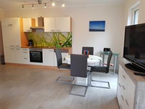 eine Küche mit einem Tisch und Stühlen sowie einem TV in der Unterkunft Ferienwohnung Inselglück in Ahlbeck