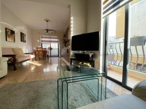 a living room with a glass table and a television at May Flower: Modern Flat close to Airport/Bus Stops in Tarxien