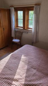 a bedroom with a bed and a chair and windows at Gut Hanerau, Erlenufer keine Monteure in Hanerau-Hademarschen