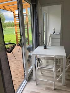 a white table and chair on a porch with a patio at Makosieje Resort-komfortowy domek 15m od jeziora,widok na jezioro,ogrzewanie,wi-fi in Makosieje