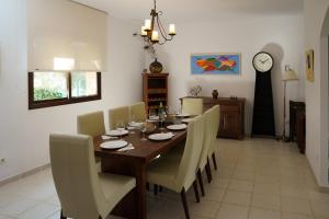 een eetkamer met een tafel en stoelen en een klok bij TESS Villa Rio Nilo in Alhaurín de la Torre