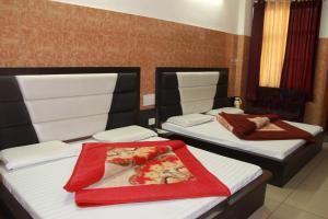 two beds in a hotel room with a red blanket at AASHIRWAD HOTEL in Katra