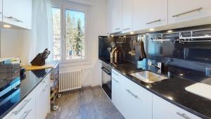 a kitchen with white cabinets and a black counter top at Alpensonne in St. Moritz