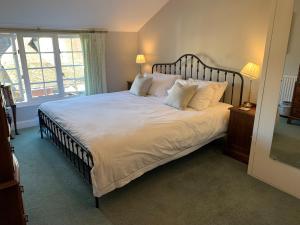 1 dormitorio con 1 cama grande con sábanas y almohadas blancas en Centre Chipping Campden - 3 Bedroom Cottage for 5, en Chipping Campden