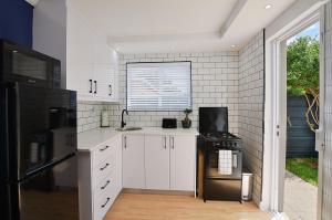 a kitchen with white cabinets and a black stove at Flatlet 2.1km from Iconic Blaauwberg Beach in Cape Town