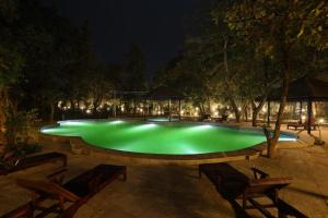 uma grande piscina com água verde à noite em Sterling Padam Pench em Khawāsa