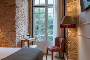 Boemio FLH Hotels في لشبونة: غرفة نوم بسرير وكرسي ونافذة
