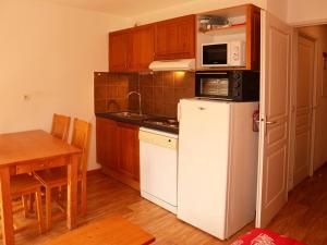 a kitchen with a white refrigerator and a table at Appartement Les Orres, 2 pièces, 4 personnes - FR-1-322-425 in Les Orres