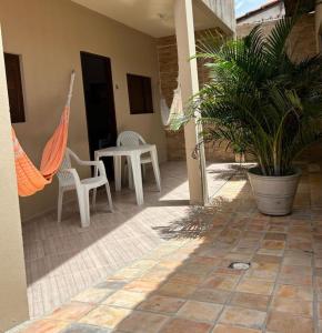 eine Terrasse mit einem Tisch, Stühlen und einer Pflanze in der Unterkunft Residencial Sibaúma in Pipa