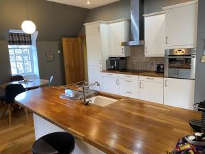 uma cozinha com armários brancos e um balcão de madeira em Glengorm Castle em Tobermory