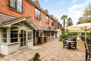 a patio with tables and chairs and a building at Inn on the Lake by Innkeeper's Collection in Godalming