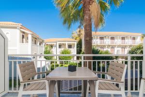 a table and chairs on a balcony with a palm tree at Cavo Doro in Kalamaki